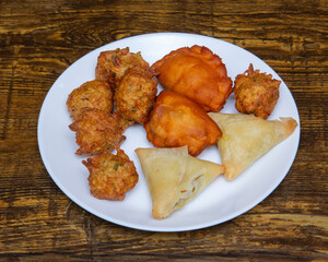 Assorted fried snacks served on a white plate atop a wooden surface