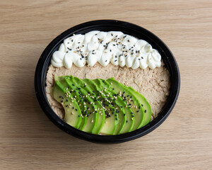 Close up of tuna bowl with avocado and cream on a wooden table top