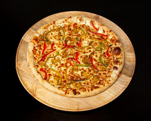 A delicious pizza with peppers and cheese on a wooden serving board