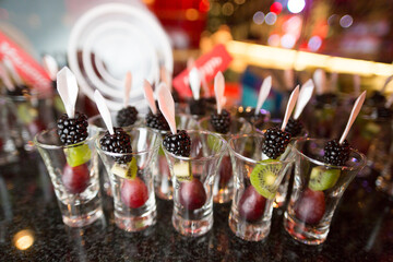 A visually appealing row of shot glasses filled to the brim with an assortment of fresh grapes,...