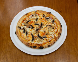 Mushroom pizza served on a white plate on a wooden table surface top