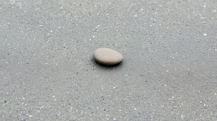Obraz premium A small, light brown rock sits on a gray concrete surface.