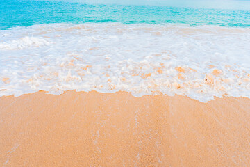 Summer paradise scene with turquoise sea, waves, and white beach sand under a bright sky.