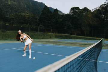Young female athlete playing tennis on a blue court, showcasing determination and energy while...
