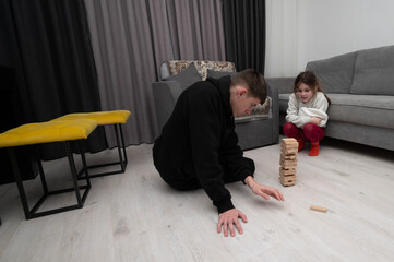 Two players engaged in a strategic game of tower blocks in a cozy living room, showcasing focus and...