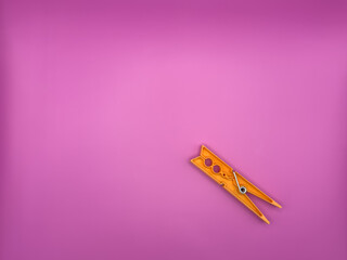 Modern orange plastic clothespin on purple background without unnecessary objects top view