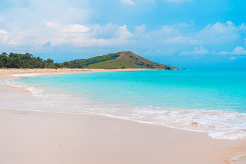Sunny sky above a peaceful tropical beach with white sand and calm turquoise water.