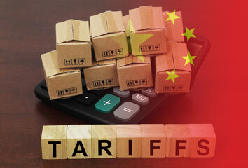 Fototapeta premium Chinese tariffs concept. Carton boxes cubes on calculator with letters tariffs and flag of China.