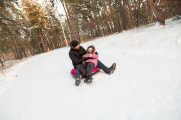 Father and daughter having fun with snow tube in the forest