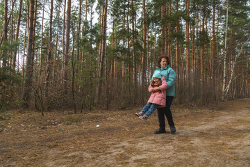 Obraz premium grandmother with granddaughter walking and playing in nature in the forest