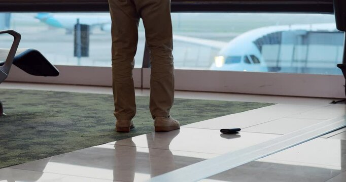 Unfocused passenger man accidentally dropping wallet on floor at airport terminal, distracted of something when handling personal items. But he was lucky, he noticed it and bent down to pick it up