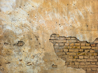 Old brick wall with peeling plaster and exposed bricks