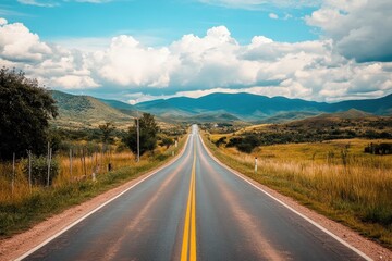 Fototapeta premium Straight road into distant mountains under a blue sky