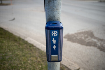 Pedestrian crossing button mounted on a metal pole beside a road