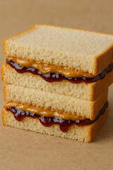 A simple PB&J sandwich on white bread, cut in half, with peanut butter and grape jelly peeking from the edges