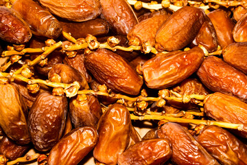 Close-up of a cluster of shiny, amber-colored Deglet Nour dates still attached to their thin, light brown stems. Dried fruit.