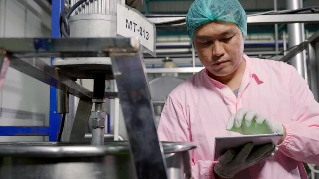 Worker using tablet in beverage factory oversees soda water filling while an engineer ensures precise quality control. Maintaining high industry standards in bottle manufacturing is paramount.