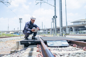 Technician inspects railroad tracks with digital equipment
