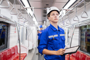 Portrait of young engineer of electric locomotive holding tablet in train