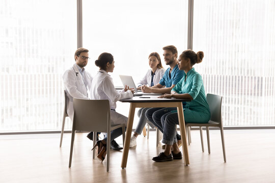 Team decision making. Multiethnic diverse doctors group of different specialities meeting brainstorming on staff briefing conference teamworking on research discuss patient diagnosis treatment ideas