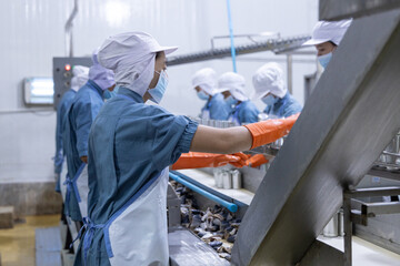 Fototapeta premium Workers processing fish in a canning factory