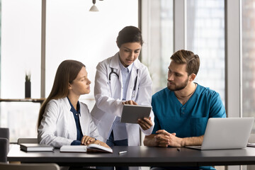Mentorship in healthcare. Smiling young woman doctor mentor supervisor teach diverse couple interns...