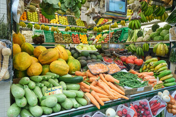 Vibrant and colorful arrangement of exotic tropical fruits displayed at a local market stall. The variety includes dragon fruit, papaya, coconut, avocado, cherimoya, passion fruit, citrus, and more, s