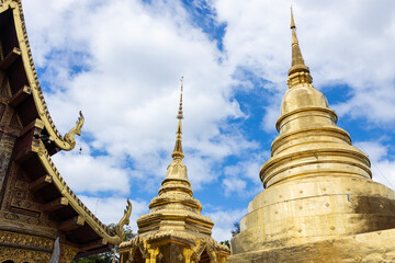 Naklejka premium Golden pagodas at Thai temple under cloudy sky