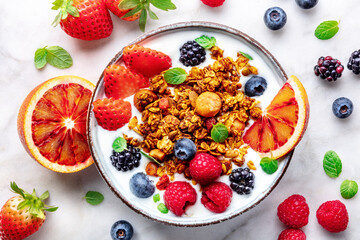 Granola with yogurt and fresh fruit. Organic gourmet muesli, overhead flat lay shot on a marble table, with ingredients