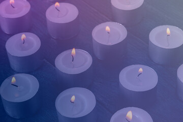 Tea light candles on a dark background, many lights in the dark, candlelight, toned image