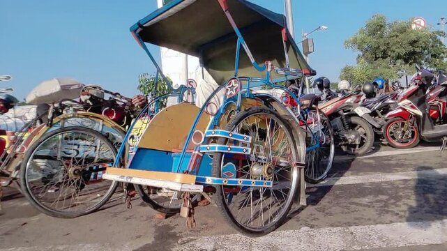 Cinematic shot of a colorful vibrant paintings decorated rickshaw existingly parked among motorcycles in Pemalang, Indonesia. Old School transportation mode concept