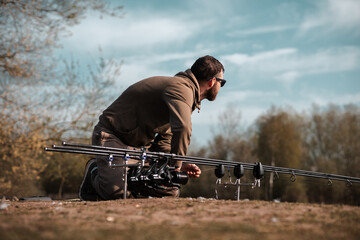 Fishing scene, carp fisherman on a lake angling with rods