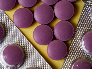 lilac pills and medicinal vitamins in a package on a yellow background