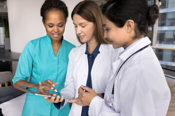 Teamwork and brainstorming. Medical team three multiethnic young females study electronic case...