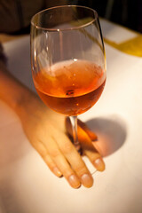 A womans hand is gracefully holding a glass of wine placed elegantly on a table, ready for an enjoyable drinking experience