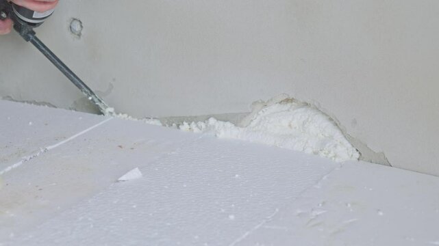 Construction worker removing excess polyurethane foam with oscillating multi-tool