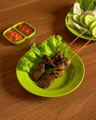Grilled Chicken Liver and Gizzard Skewers with Fresh Vegetables and Spicy Sambal on a Green Plate. Sate Ati Ampela