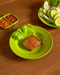Traditional Sundanese Sweet and Spiced Fried Beef Served with Fresh Vegetables and Sambal for a Rich and Flavorful Indonesian Dish.