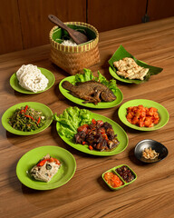 Sundanese Family Meal with Assorted Traditional Foods: Fried Fish, Beef Stir Fry, Sambal, Rice, and Side Dishes.