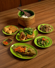 Sundanese Family Meal with Assorted Traditional Foods: Nila Fish Pesmol, Fried Chicken, Sambal, Rice, and Side Dishes.