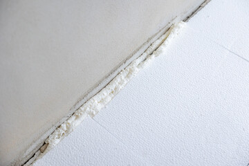 Construction worker applying polyurethane expanding foam insulation to floor and wall joint