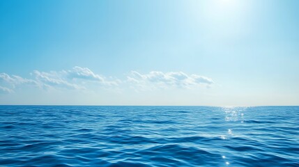 Fototapeta premium Ocean water under a blue sky with sunlight reflection and some clouds.