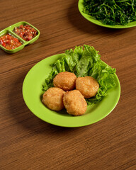 Perkedel, Indonesian Mashed Potato Fritters Served with Fresh Greens and Spicy Chili Sambal for a Flavorful Traditional Side Dish.