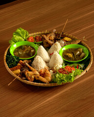 Authentic Sundanese Feast with Assorted Dishes: Rice, Fried Chicken, Salted Fish, Fresh Vegetables, Soups, and Sambal.