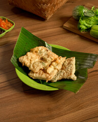 Tempeh Mendoan Served on Banana Leaf with Fresh Vegetable Sides and Spicy Sambal, a Traditional Indonesian Delight with Authentic Flavors.