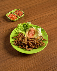 Crispy Fried Chicken Intestines Served with Vegetables and Spicy Sambal on the Side, A Flavorful Traditional Indonesian Street Food Delicacy.
