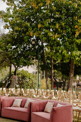 Outdoor event setup: plush sofas and chairs arranged under trees, creating an inviting ambiance for gatherings in nature's embrace.
