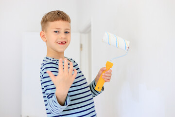 A young boy renovating a room, sanding the walls with sandpaper and painting them white with a...