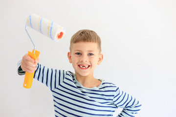 A young boy renovating a room, sanding the walls with sandpaper and painting them white with a roller. Home improvement and DIY repair concept