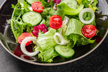 Salad vegetable tomato, cucumber, lettuce, green leaf lettuce, onion appetizer vegetable dish fresh gourmet food background rustic food top view copy space keto and paleo diet vegetarian vegan food